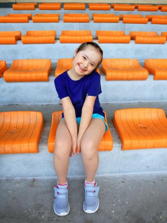 Happy young girl sitting in stadium stand