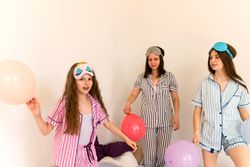 Family enjoying a balloon party in pajamas indoors.
