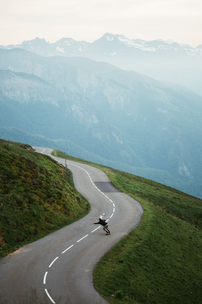 Scenic mountains view and man skateboarding on road