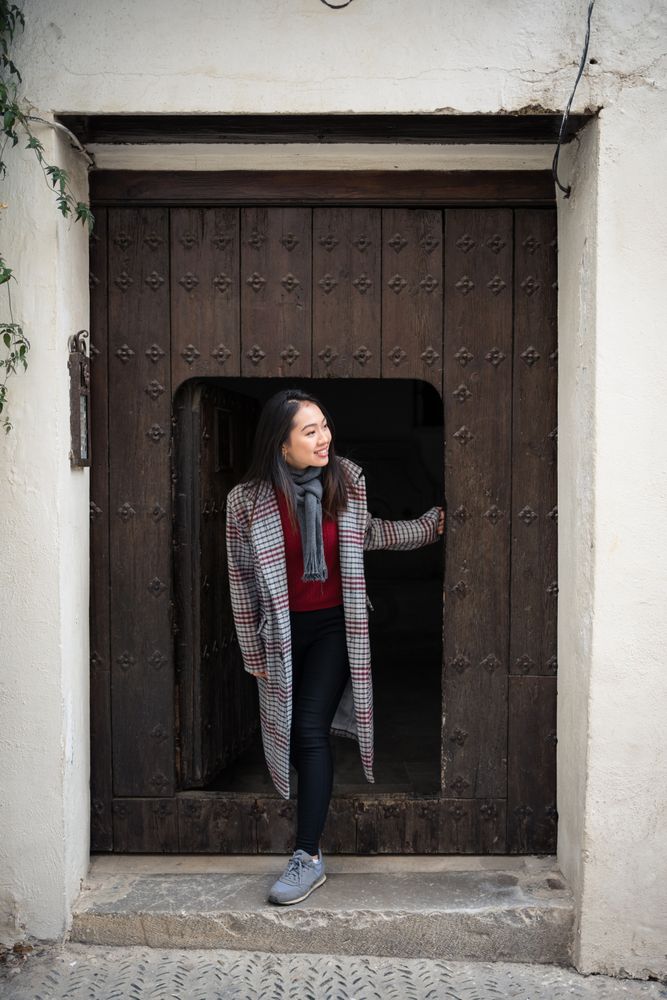 Content female tourist peering from small door of ancient building