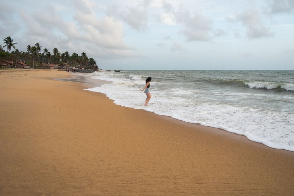 Woman in beachwear walking on sand barefoot