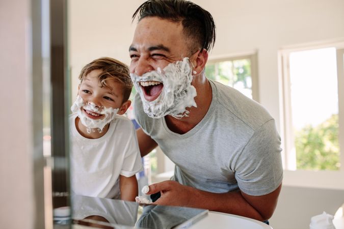 Happy father and son having fun while shaving in bathroom