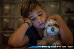 Boy looking at tablet screen while hugging a dog bY6Bj0