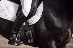 Boots of horseback rider in uniform on saddle on horse