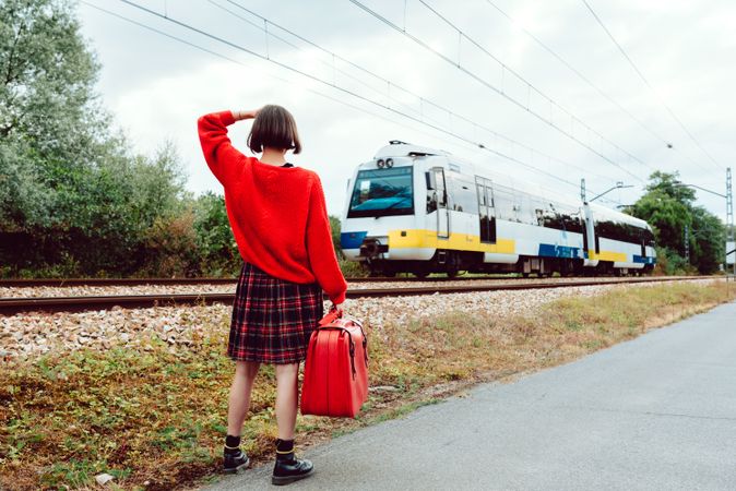 Woman looking at approaching modern train on railroad