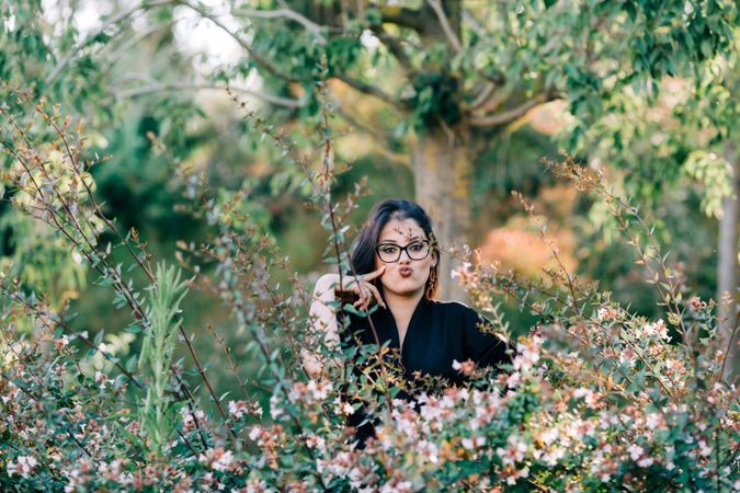 Smiling female looking at camera among green bushes