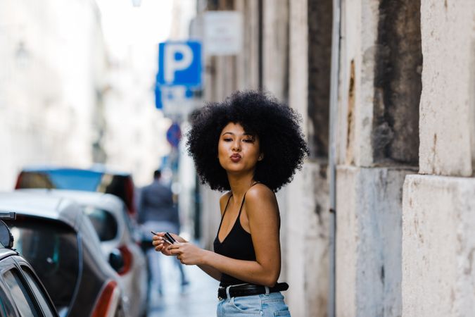 Black female applying lipstick outdoors