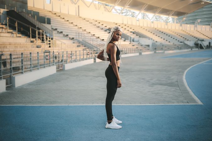 Female athlete standing inside a track and field stadium ready