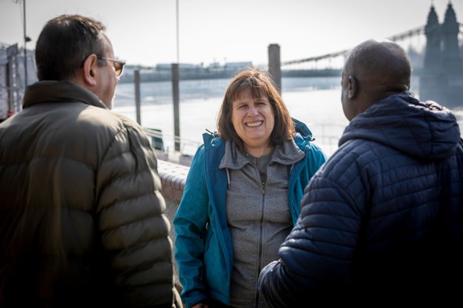 Three adults talking by the river