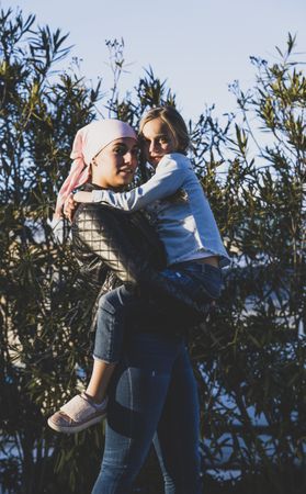 Woman in cancer head scarf holding child
