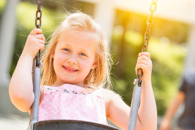 Young Girl Having Fun On The Swings At The Playground