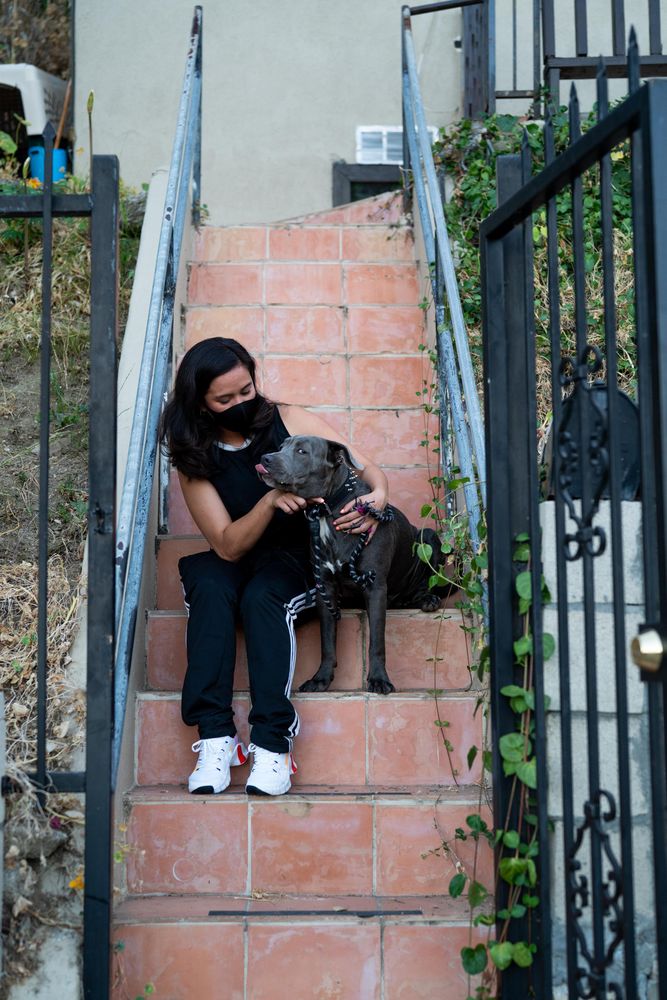 Woman sitting on outside stairs putting a leash on her dog
