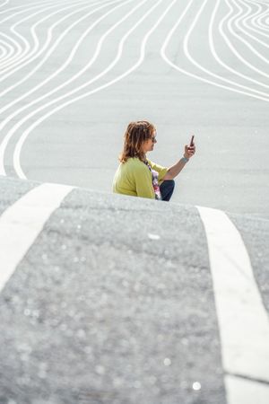 Modern relaxed woman on marked road and browsing smartphone
