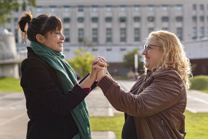 Portrait of a smiling lesbian couple holding hands and looking to each other outdoors
