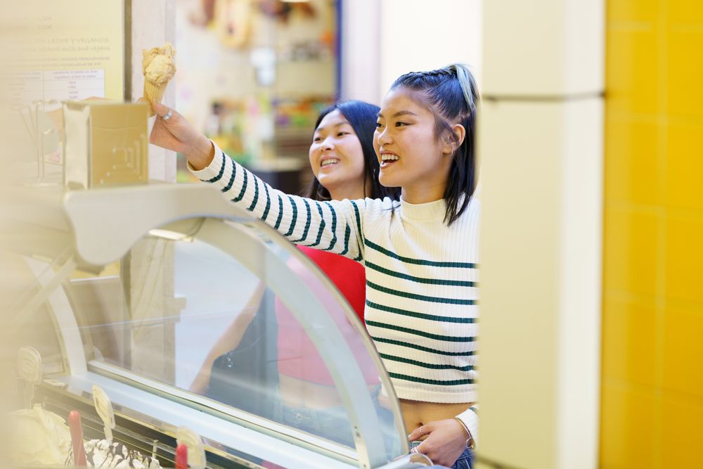 Two women buying ice cream cones on nice day