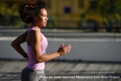 Woman with afro hairstyle running outside in sporty vest 5rlEnb