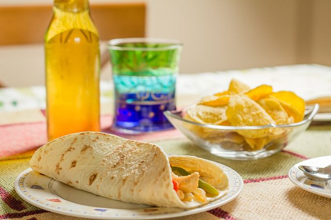 Traditional mexican food with a plate of chicken fajita, bowl of nachos and a fresh beer