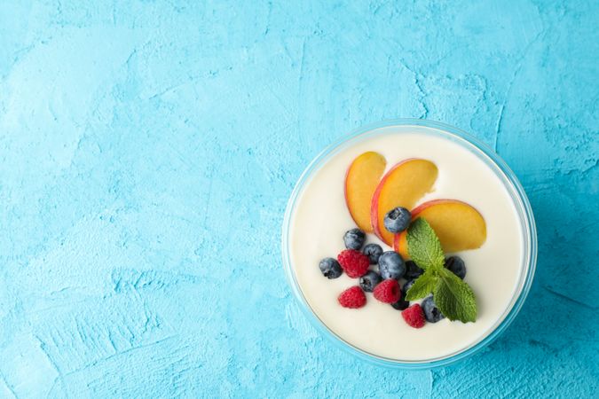 Bowl with sour cream yogurt and fruits on color background