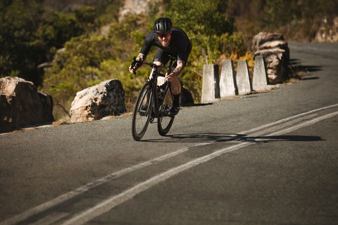 Pro biker riding his bicycle downhill on a curvy mountain road