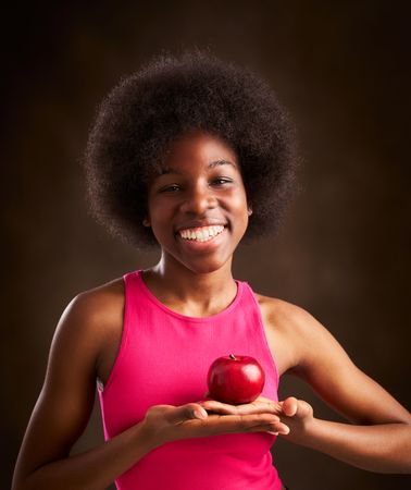 young woman with afro hairstyle happy with an apple in studio
