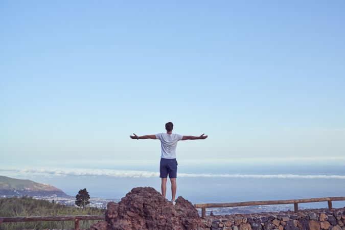 Unrecognizable man standing above town on fence