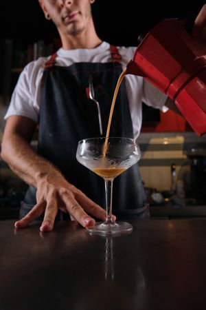Unrecognizable bartender pouring cocktail into glass