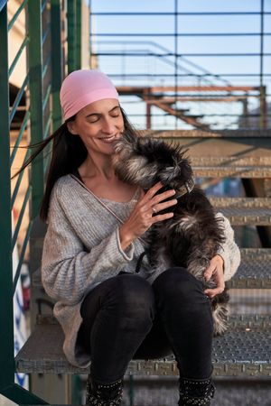 Content young person caressing fluffy dog on stairs
