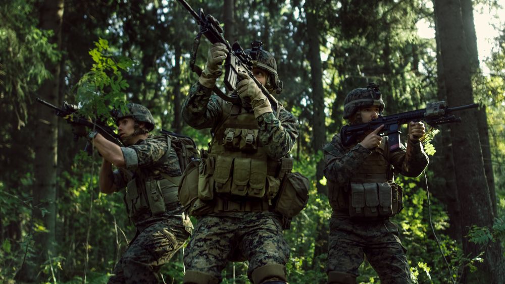 Three Fully Equipped Soldiers Wearing Camouflage Uniform Attacking Enemy, They're in Shooting Ready Stance