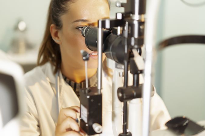 Medical woman looking through microscope