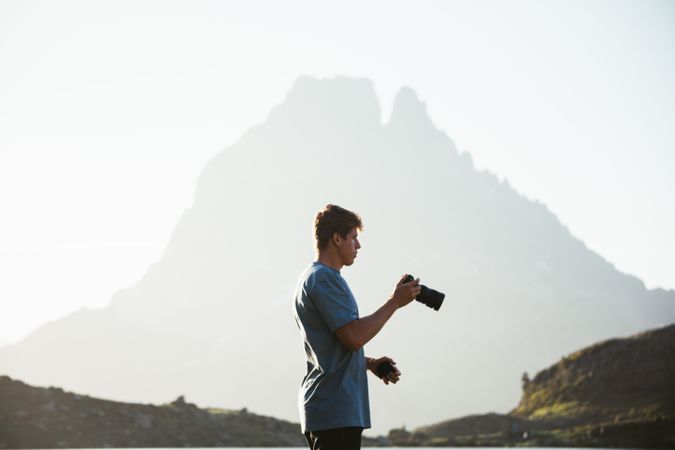 Unrecognizable man taking photo of mountain landscape