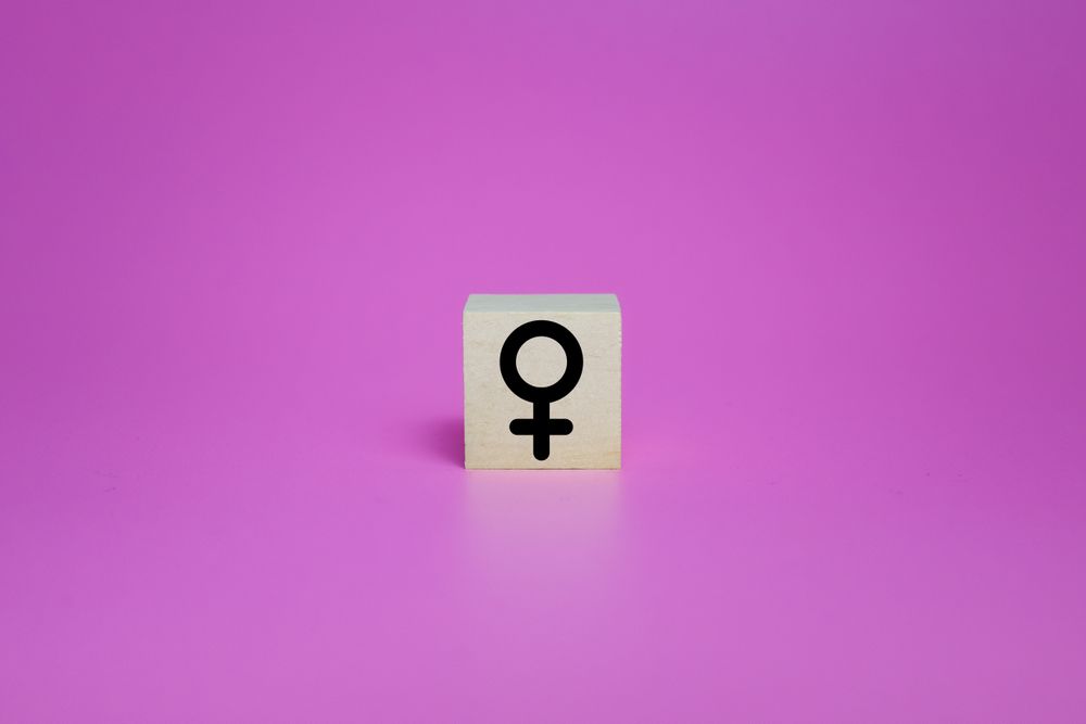 female symbol on wooden blocks isolated on pink background