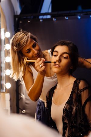 Makeup artist doing makeup for young female artist