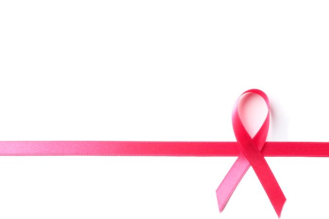 Pink awareness ribbon isolated on blank background, top view