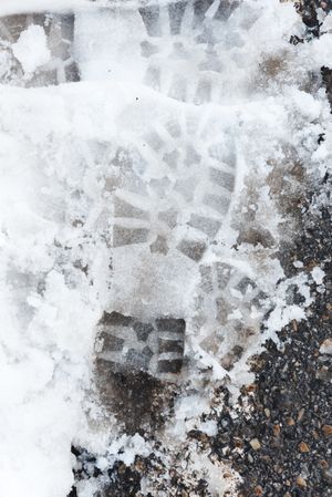 Shoe prints on wet snow on asphalt road