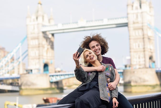 Girlfriend and boyfriend hugging for photo in front of famous British bridge