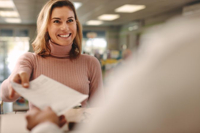 Female customer giving prescription to pharmacist at pharmacy store