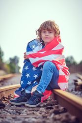 Kid wrapped in USA flag on railway