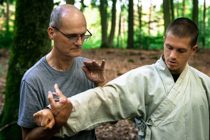 man training martial arts student in forest