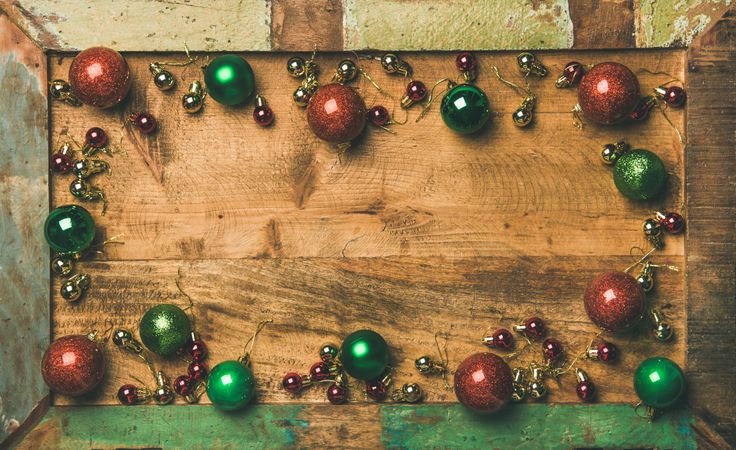 Tree ornaments arranged on wooden board, large and small red, green and gold baubles, copy space