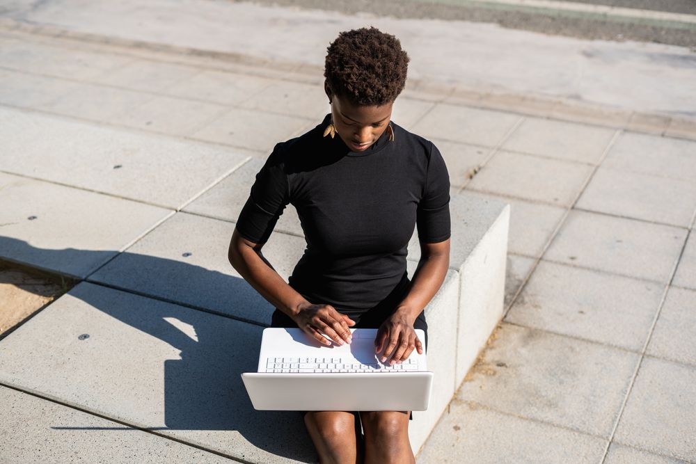 Serious female surfing laptop near modern building