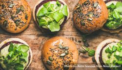 Fresh vegan burgers on seeded buns arranged on wooden board 0WNz6b
