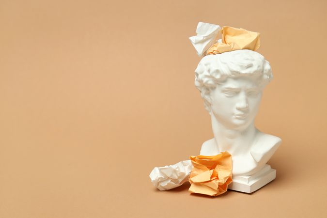 Marble bust with crumpled paper on brown background