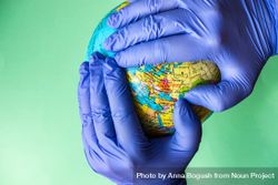 Covid-19 virus concept of hands in latex gloves holding globe 0WOrO6