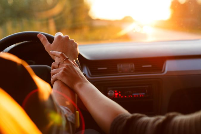 Couple holding hands while driving