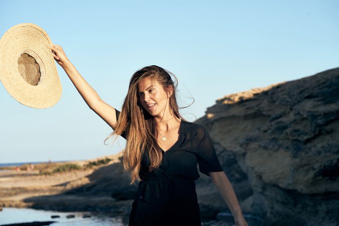 Cheerful woman holding hat in air