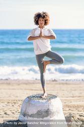 Black woman doing balance exercises on the beach 5QwQGb