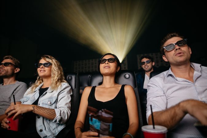 Group of young people watching 3d movie in theater