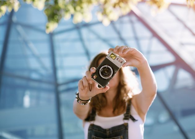 Creative woman taking photo on camera in sunny day