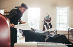 Barber applying towel to customer’s neck in barbershop 4BVAX4
