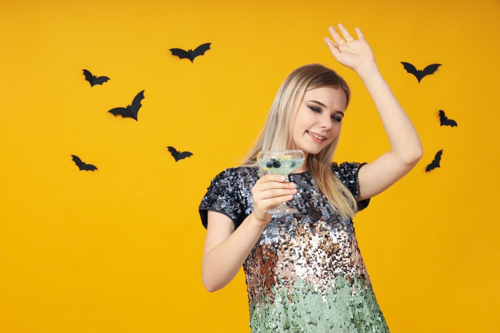 Concept of Halloween, young woman on yellow background
